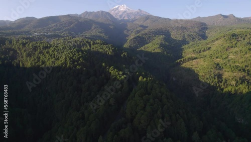 Drone video of a highway across the forest in the hills near the Pico de Orizaba volcano, with the volcano in the background photo