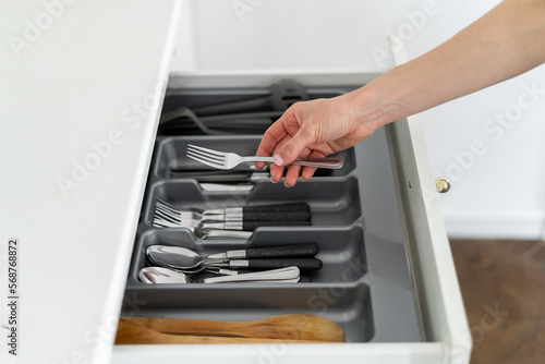 woman putting clean fork in open wooden box for storage cutlery