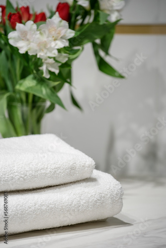 stack of terry towels and bouquet on table indoors