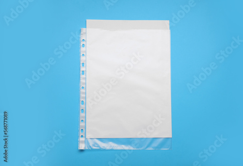 Punched pocket with paper sheet on light blue background, top view. Space for text