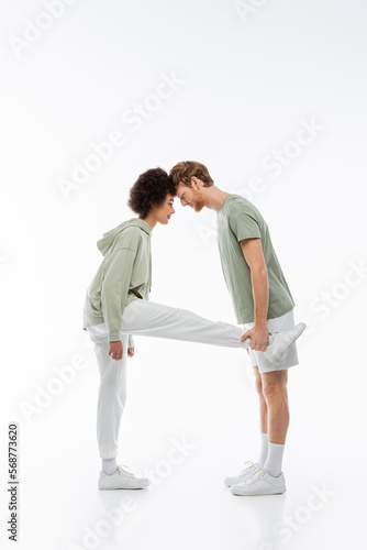 side view of interracial couple in pastel green clothes showing a letter on white background.