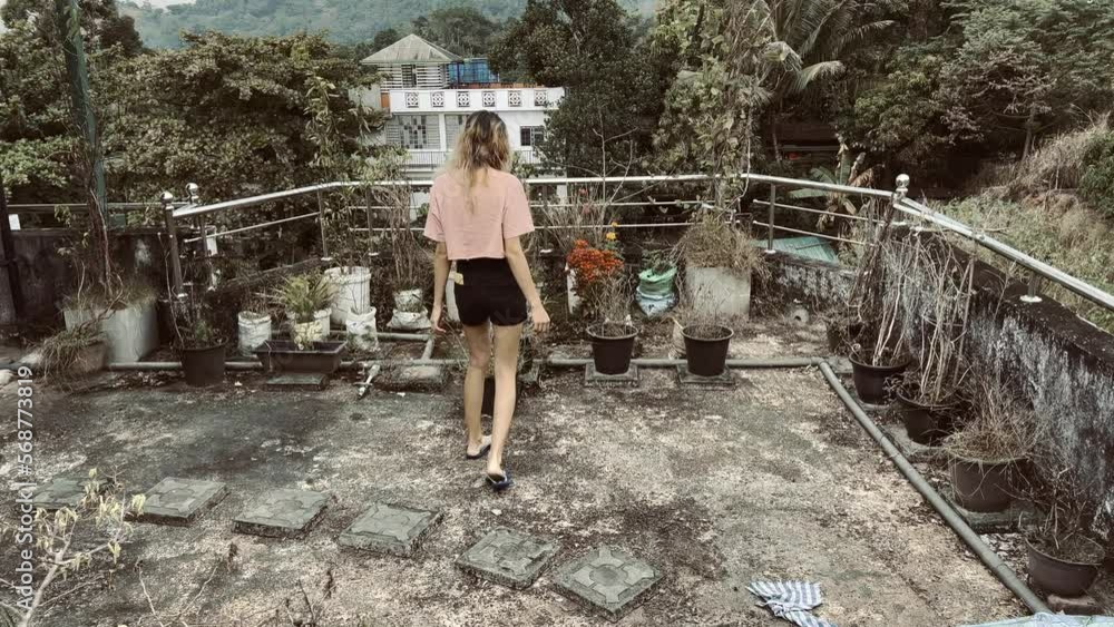 girl walking to the branches and flowers in balcony girl walking to the branches and flowers in balcony