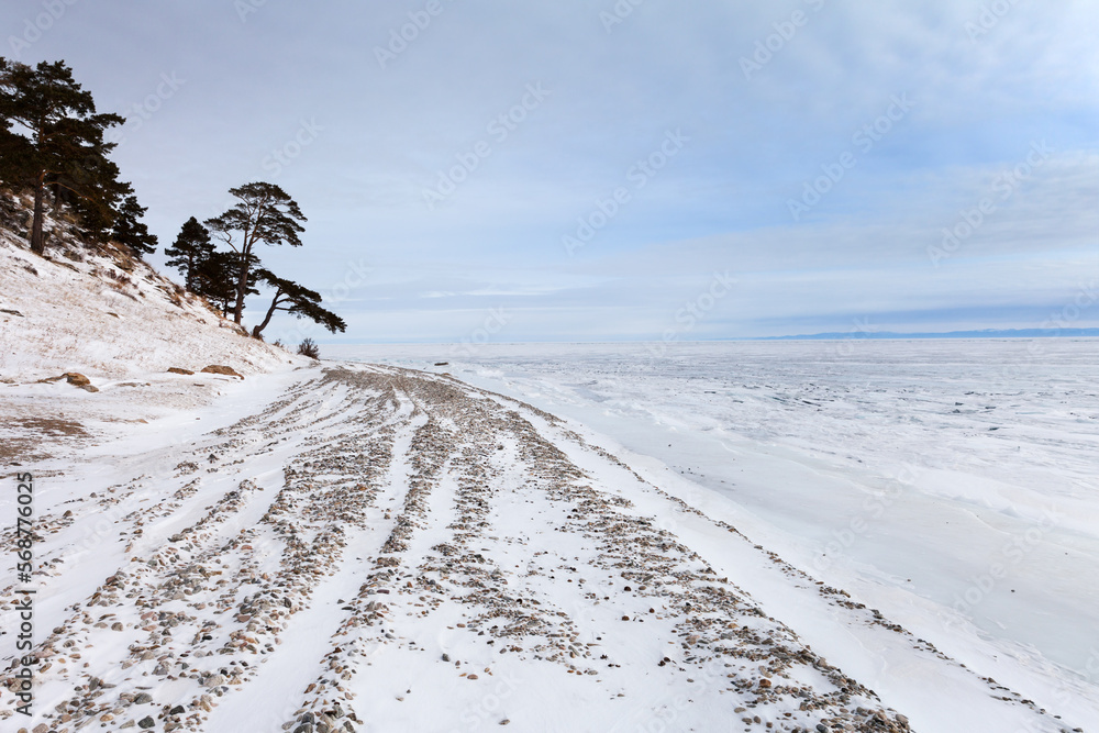 Winter landscape of a snowy beach near the coastal hills with picturesque pine trees on cold january day. Winter travel on seaside. Natural background Winter landscape of a snowy beach near the coastal hills with picturesque pine trees on cold january day. Winter travel on seaside. Natural background