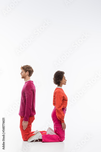 side view of interracial couple in magenta color clothes showing u letter on white background. © LIGHTFIELD STUDIOS