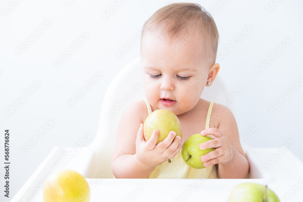 cute baby girl in baby chair eating apples. Baby first solid food cute baby girl in baby chair eating apples. Baby first solid food