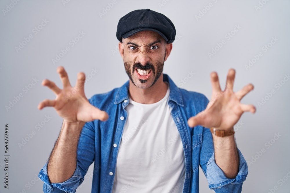 Hispanic man with beard standing over isolated background smiling funny doing claw gesture as cat, aggressive and sexy expression Hispanic man with beard standing over isolated background smiling funny doing claw gesture as cat, aggressive and sexy expression