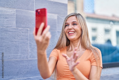 Young blonde woman smiling confident having video call at street