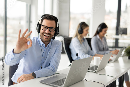 Cuadro en lienzo Portrait of handsome bearded business man with headset showing OK sing at call c