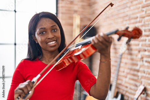 Young african american woman musician playing violin at music studio