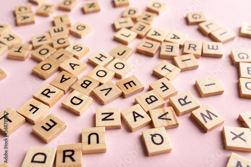 Top view of square wooden tiles with the English alphabet lying on a pink background. The concept of developing thinking, grammar, back to school, learning