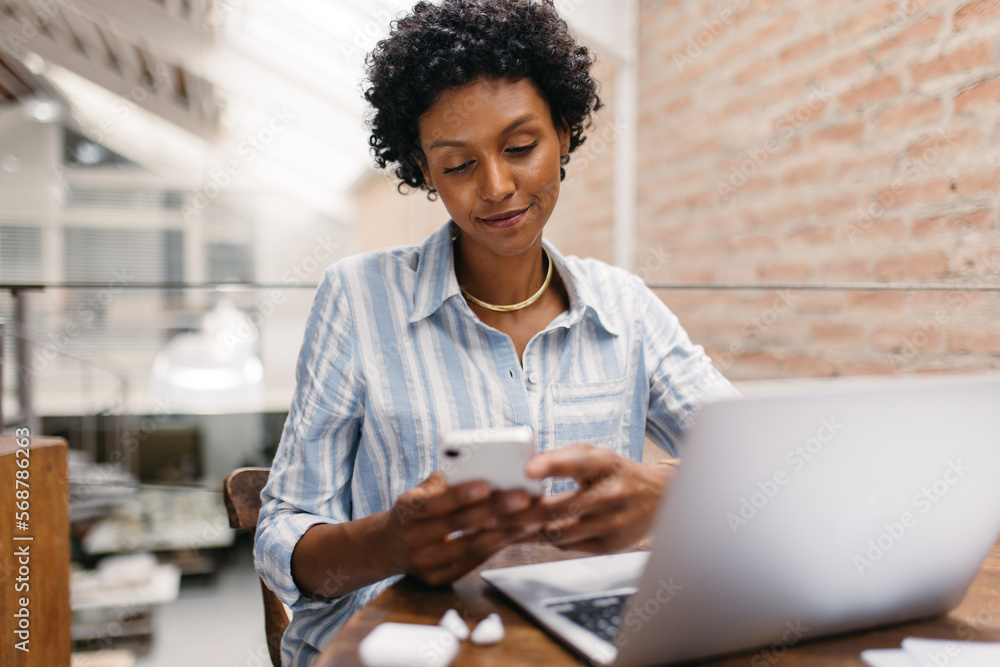 Small business owner using a smartphone in a warehouse Small business owner using a smartphone in a warehouse