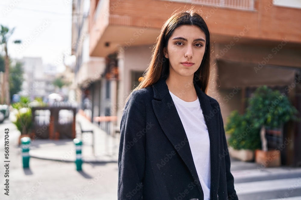 Fototapeta premium Young beautiful hispanic woman standing with serious expression at street