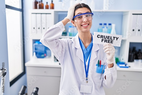 Young beautiful woman working on cruelty free laboratory stressed and frustrated with hand on head  surprised and angry face