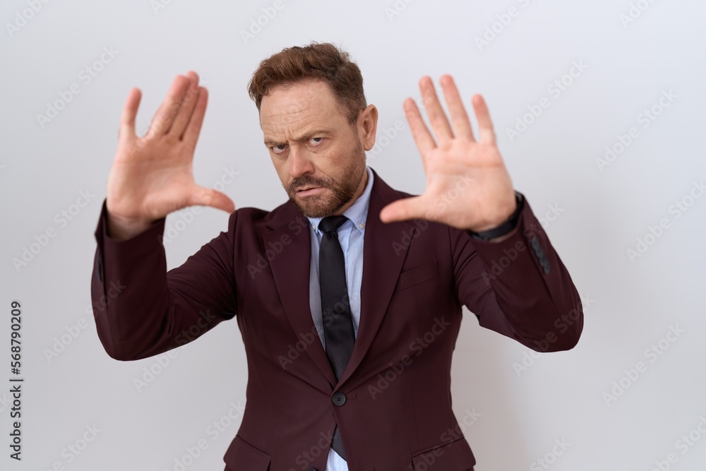 Middle age business man with beard wearing suit and tie doing frame using hands palms and fingers, camera perspective Middle age business man with beard wearing suit and tie doing frame using hands palms and fingers, camera perspective