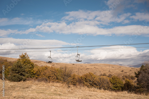 empty two ropeway chairs of mountain ski resort in autumn photo