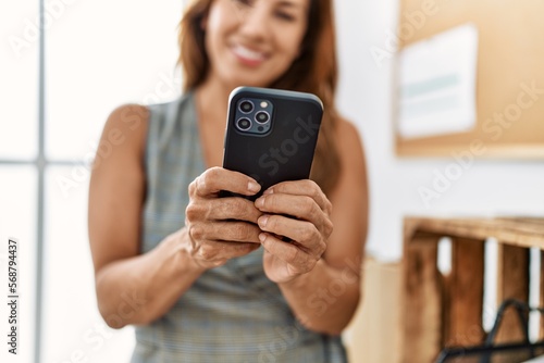Young latin woman business worker using smartphone at office
