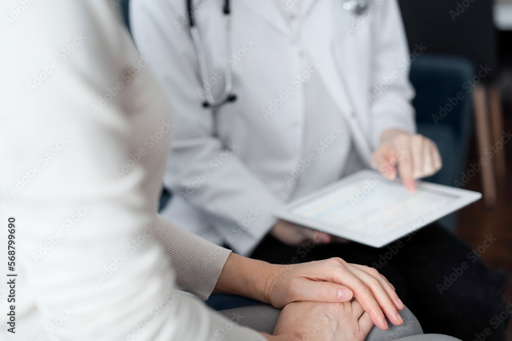 Doctor and patient sitting at sofa in clinic office. The focus is on female woman's hands, close up. Medicine concept Doctor and patient sitting at sofa in clinic office. The focus is on female woman's hands, close up. Medicine concept