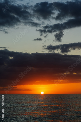 Horizontal photo of the sunset over the sea. Clouds in the sky in the evening  bright sun.