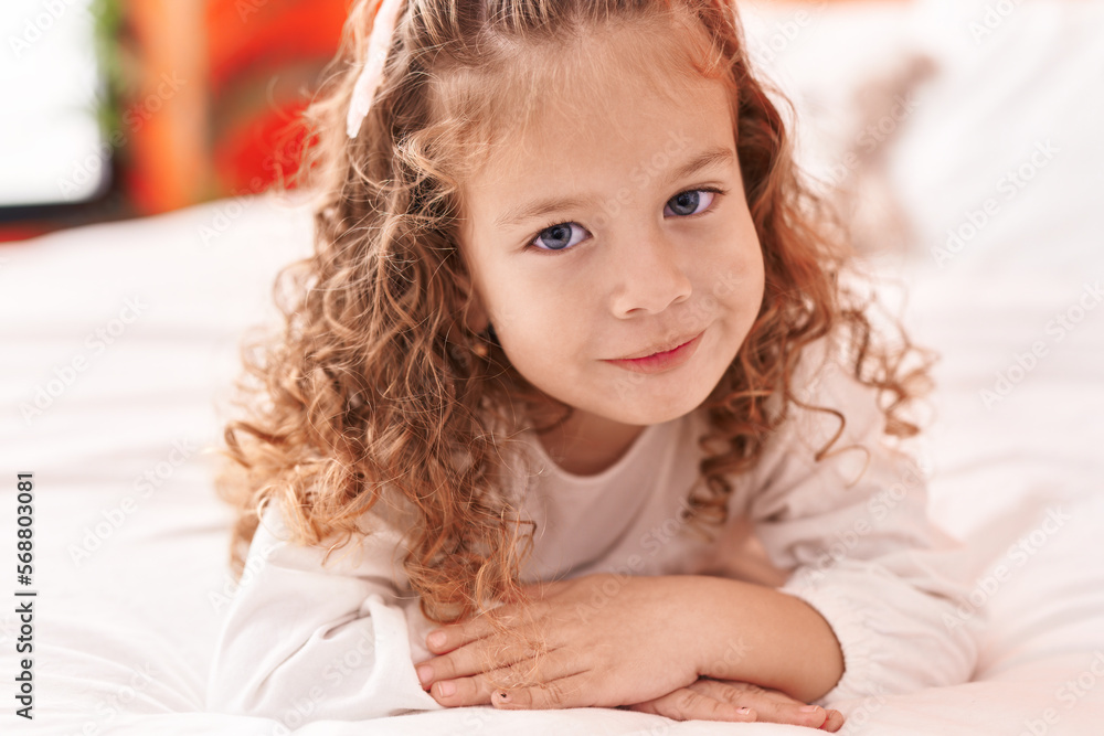 Fototapeta premium Adorable blonde toddler smiling confident lying on bed at bedroom
