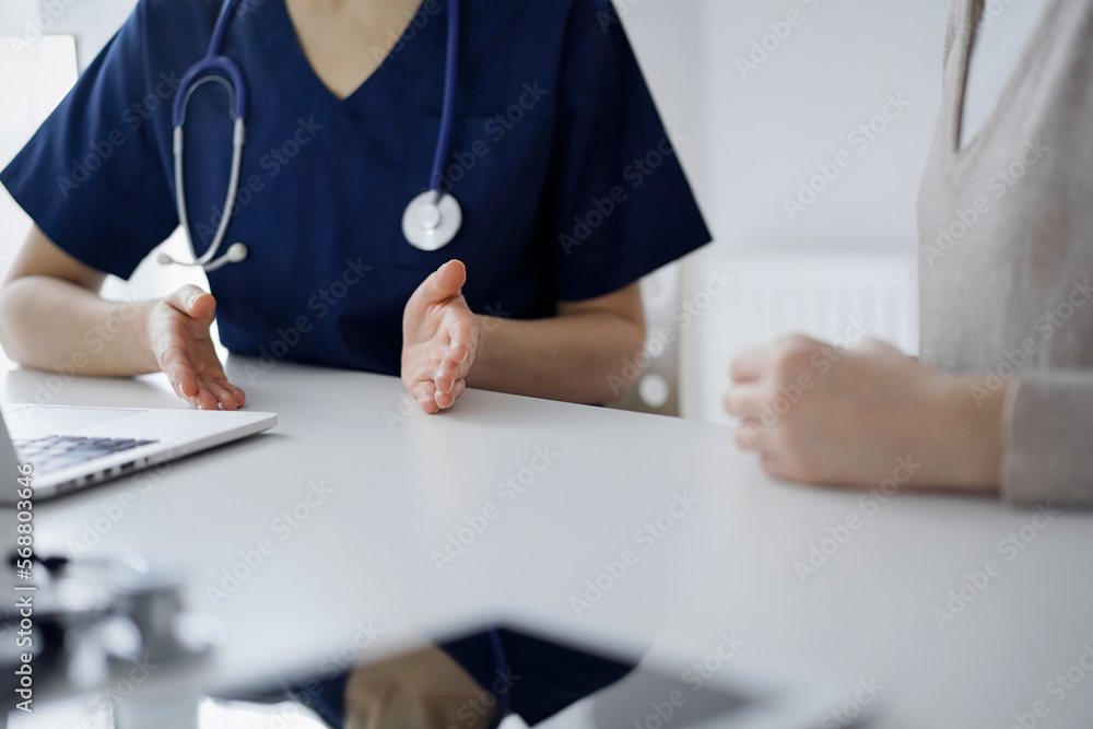 Doctor and patient talking to each other during current health examination while sitting at the desk in clinic, closeup of hand. Perfect medical service and medicine concept Doctor and patient talking to each other during current health examination while sitting at the desk in clinic, closeup of hand. Perfect medical service and medicine concept