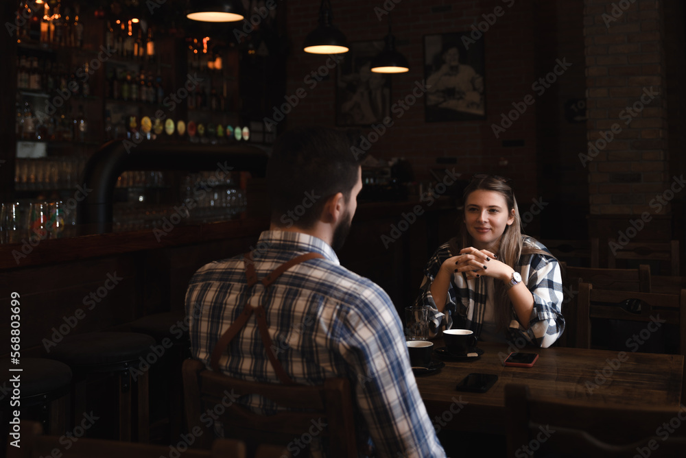 Confident owner of cafe interviewing young specialist. Manager of cafeteria or coffee shop job interview with young male bartender barista or waiter applied for work in the restaurant. Employee hiring