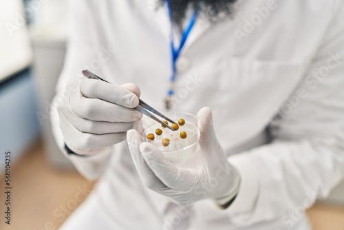 Young african american man wearing scientist uniform using tweezer at laboratory