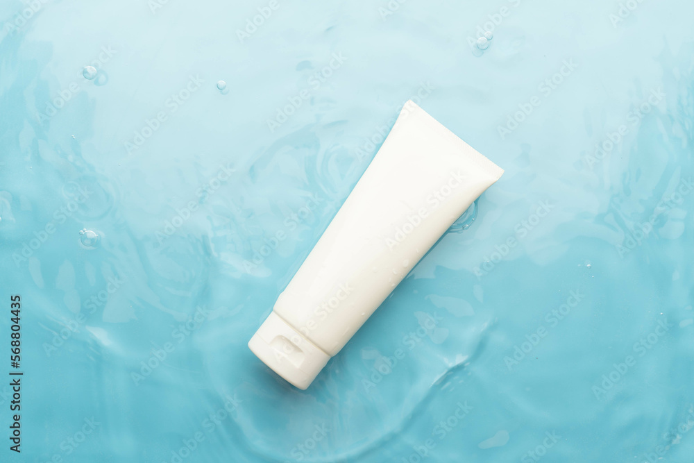 Blank white squeeze bottle plastic tube on blue water surface wtih waves. Packaging of moisturizing cream, cleansing gel or hydrating body lotion. Spa and skincare product branding mock up. Blank white squeeze bottle plastic tube on blue water surface wtih waves. Packaging of moisturizing cream, cleansing gel or hydrating body lotion. Spa and skincare product branding mock up.
