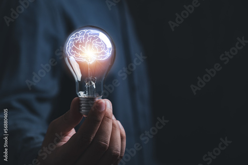 businessman Hand holding light bulb with brain glowing with orange light line and ray. Creative and new business knowledge thinking idea concept.