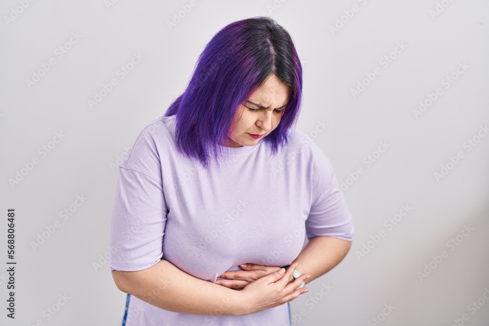 Obraz premium Plus size woman wit purple hair standing over isolated background with hand on stomach because nausea, painful disease feeling unwell. ache concept.