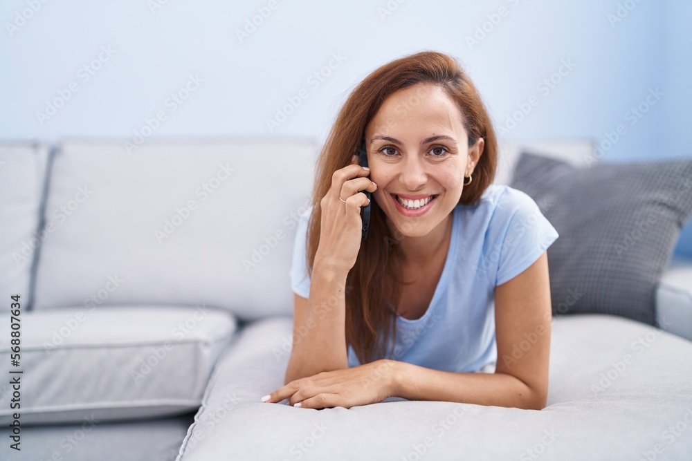 Young woman talking on the smartphone lying on sofa at home Young woman talking on the smartphone lying on sofa at home