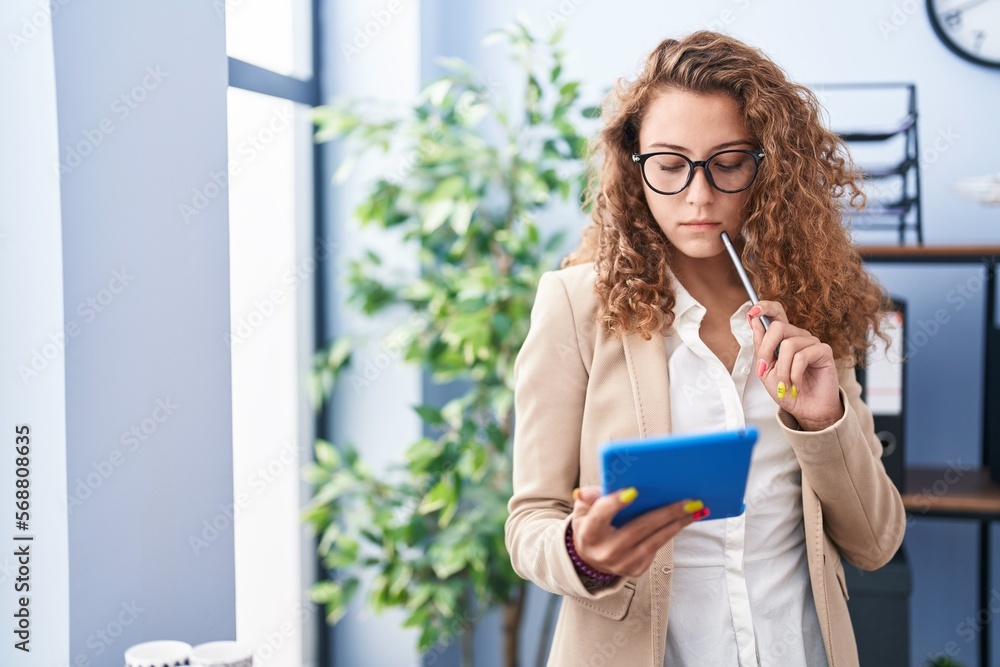 Young beautiful hispanic woman business worker using touchpad with serious expression at office Young beautiful hispanic woman business worker using touchpad with serious expression at office