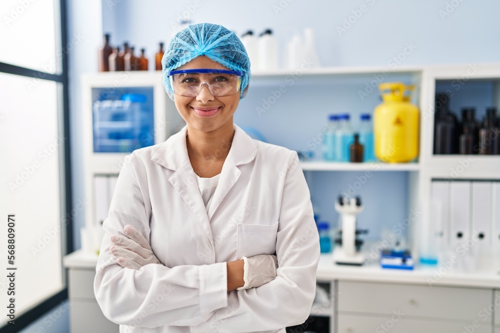 Young latin woman wearing scientist uniform standing with arms crossed gesture at laboratory Young latin woman wearing scientist uniform standing with arms crossed gesture at laboratory