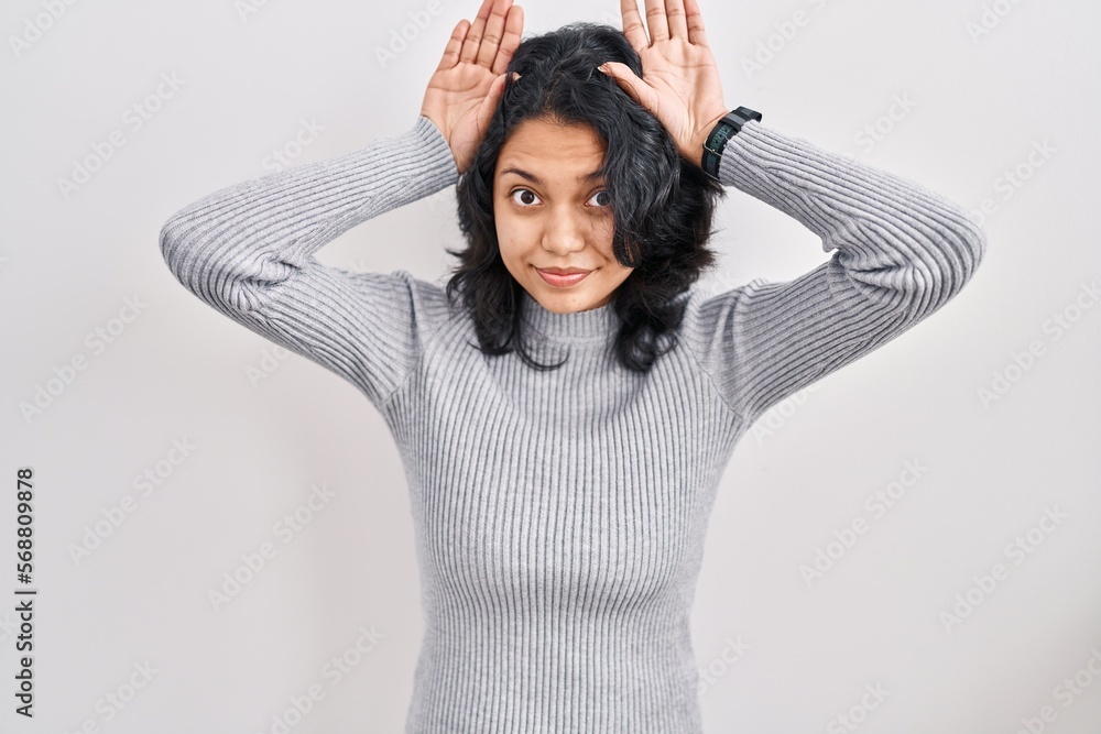 Hispanic woman with dark hair standing over isolated background doing bunny ears gesture with hands palms looking cynical and skeptical. easter rabbit concept. Hispanic woman with dark hair standing over isolated background doing bunny ears gesture with hands palms looking cynical and skeptical. easter rabbit concept.