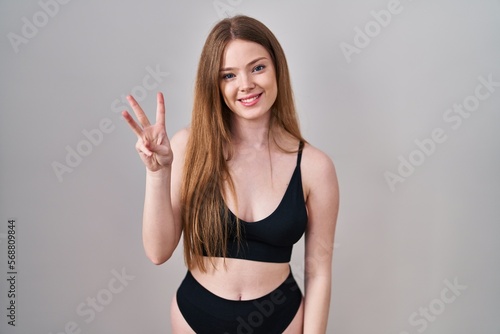 Young caucasian woman wearing lingerie showing and pointing up with fingers number three while smiling confident and happy. © Krakenimages.com