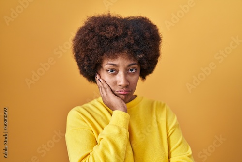 Young african american woman standing over yellow background thinking looking tired and bored with depression problems with crossed arms. © Krakenimages.com