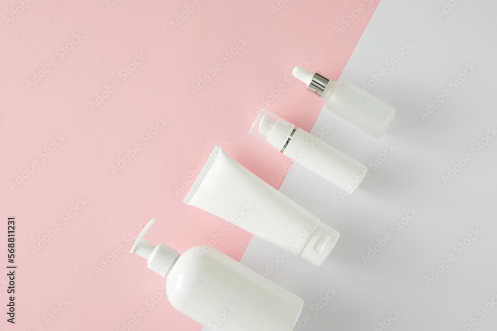 Skin care products concept. Flat lay photo of white cosmetic bottles without label on pastel pink and white background with empty space. Beauty cosmetics mockup idea. Skin care products concept. Flat lay photo of white cosmetic bottles without label on pastel pink and white background with empty space. Beauty cosmetics mockup idea.