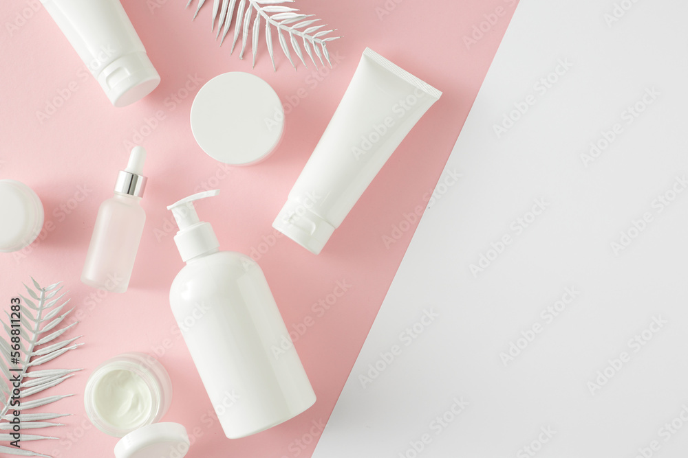 Summer skincare concept. Top view photo of cosmetic tubes, dropper bottle, pump bottle and tropical leaves on pastel pink and white background with empty space. Flat lay cosmetics mockup idea. Summer skincare concept. Top view photo of cosmetic tubes, dropper bottle, pump bottle and tropical leaves on pastel pink and white background with empty space. Flat lay cosmetics mockup idea.
