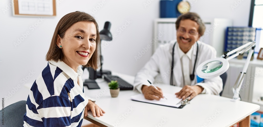 Obraz premium Middle age man and woman wearing doctor uniform having medical consultation at clinic