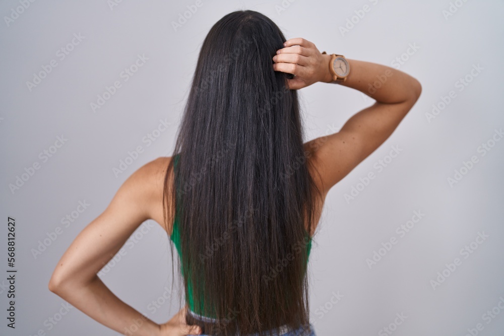 Young woman standing over isolated background backwards thinking about doubt with hand on head Young woman standing over isolated background backwards thinking about doubt with hand on head