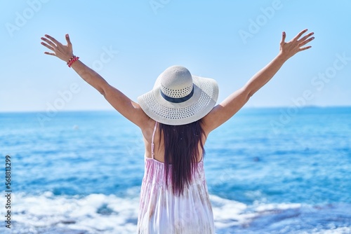 Fotobehang Young beautiful hispanic woman tourist leaning on balustrade at seaside