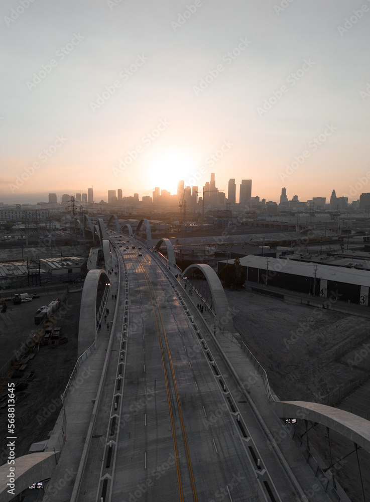 A cityscape view of the 6th street bridge and the downtown district skyline in Los Angeles during the sunset