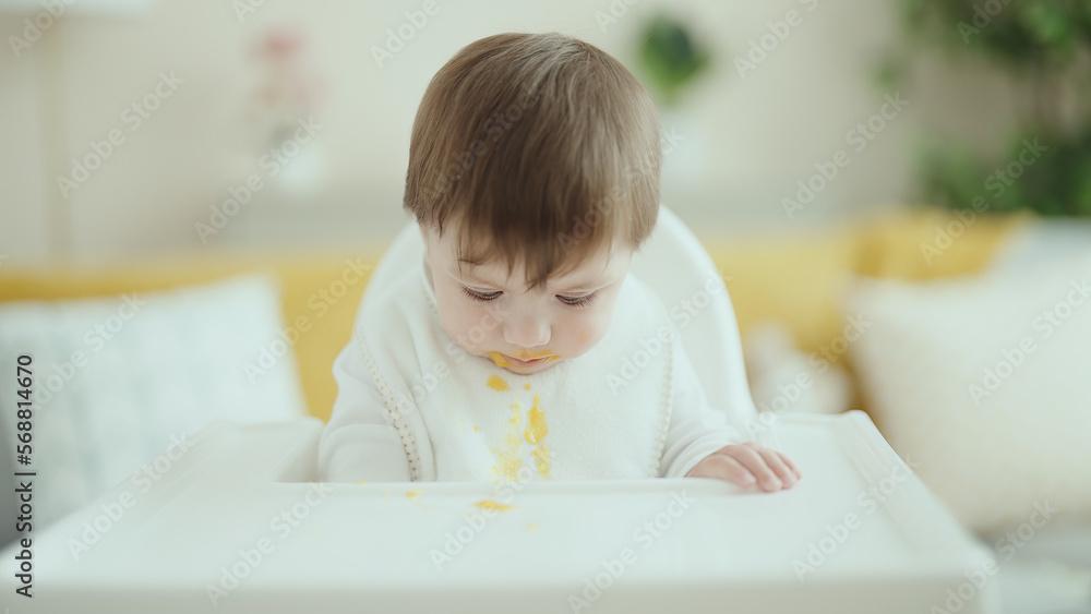 Adorable hispanic toddler sitting on highchair eating food at home Adorable hispanic toddler sitting on highchair eating food at home