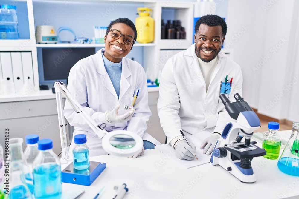 Man and woman scientists writing on notebook working at laboratory Man and woman scientists writing on notebook working at laboratory