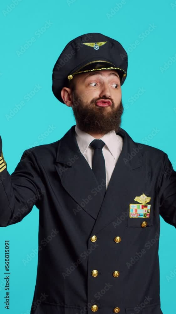 Vertical video: Caucasian man having fun with origami and toy aircraft, playing with folded paper plane and fake miniature in studio. Young aviator in flying industry uniform posing over blue Vertical video: Caucasian man having fun with origami and toy aircraft, playing with folded paper plane and fake miniature in studio. Young aviator in flying industry uniform posing over blue