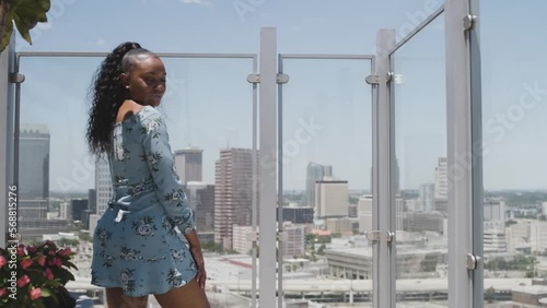 Black Stock Footage of happy, healthy, and successful Black woman wearing a sun dress on a luxury condominium rooftop on a sunny blue sky day