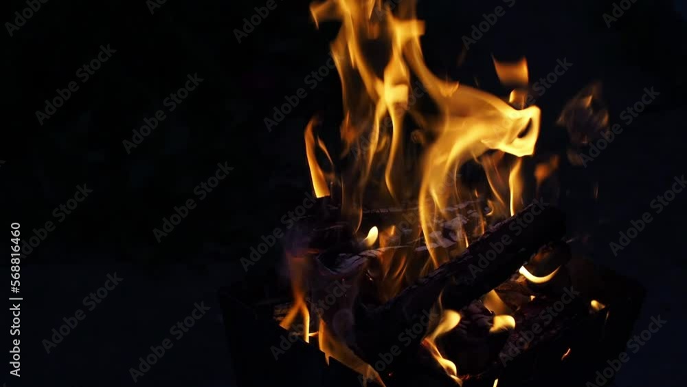 Evening open fire flame outdoors. Red flames of campfire on dark ground at campsite in wild at overcast. Closeup bonfire with firewood on backdrop. Selective focus. Autumn relax camping mood. Footage Evening open fire flame outdoors. Red flames of campfire on dark ground at campsite in wild at overcast. Closeup bonfire with firewood on backdrop. Selective focus. Autumn relax camping mood. Footage