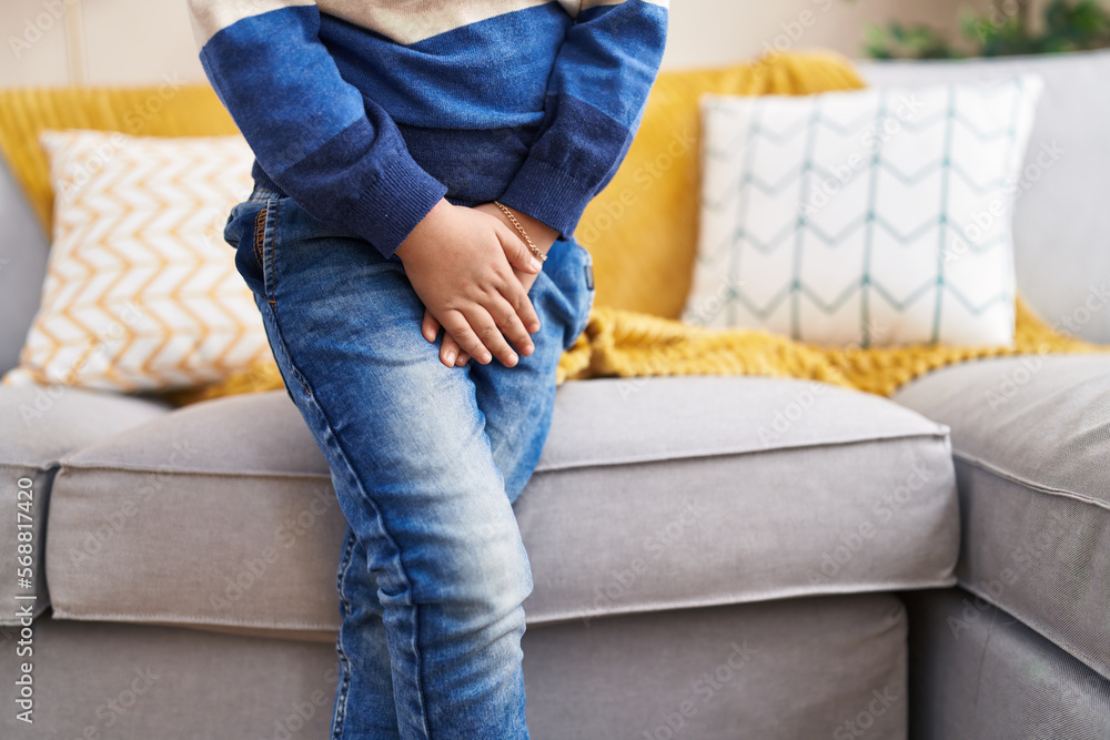 Adorable hispanic boy covering his genitals with hands at home Adorable hispanic boy covering his genitals with hands at home