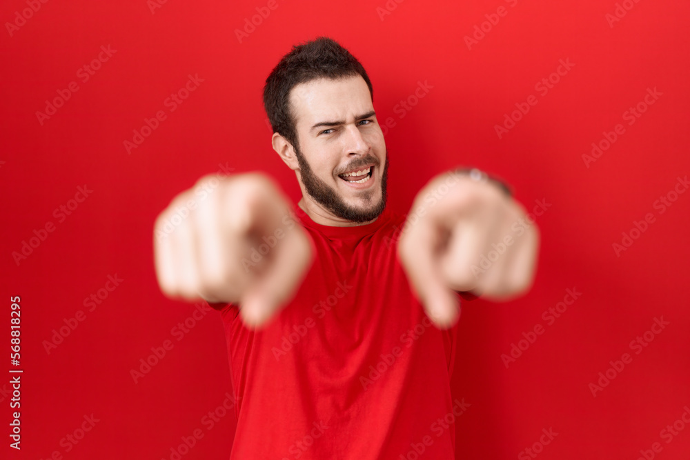 Young hispanic man wearing casual red t shirt pointing to you and the camera with fingers, smiling positive and cheerful