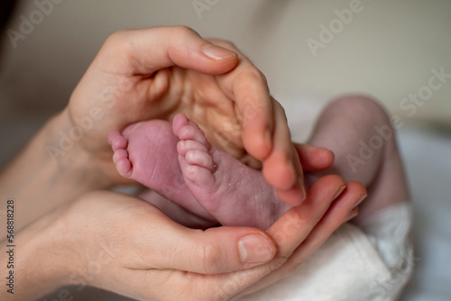 Woman hands holding new born baby feet