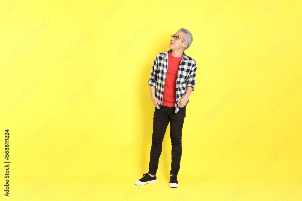 The 40s adult Asian man with casual dressed standing on the yellow background.